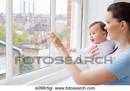 Stock Image - Mother and baby looking through a window. Fotosearch