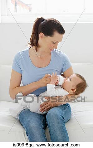Stock Image - Mother bottle feeding baby. Fotosearch