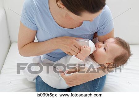 Stock Photo - Mother bottle feeding baby. Fotosearch