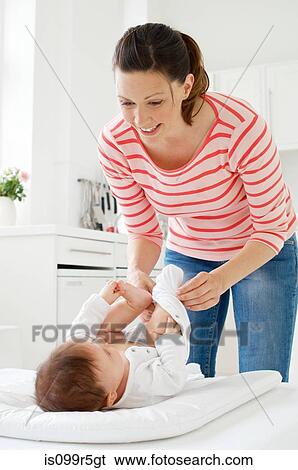 Mother changing baby daughter View Large Photo Image Stock Photograph - Mother changing baby daughter. Fotosearch