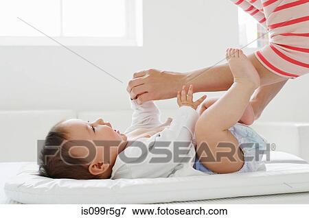 Mother changing baby girl on mat View Large Photo Image Stock Photo - Mother changing baby girl on mat. Fotosearch