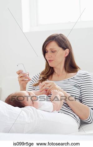 Mother holding baby and using cellphone View Large Photo Image Stock Image - Mother holding baby and using cellphone. Fotosearch