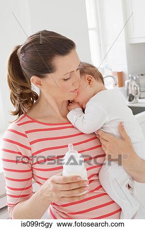Mother holding baby girl and bottle View Large Photo Image Stock Photo - Mother holding baby girl and bottle. Fotosearch