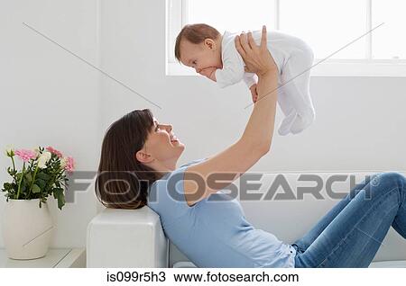 Stock Image - Mother lifting up baby girl. Fotosearch