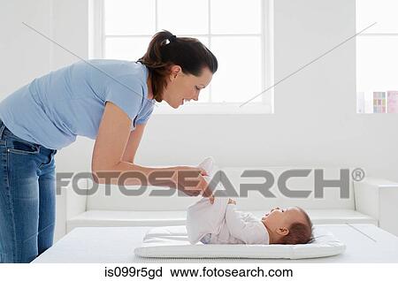 Stock Image - Mother with baby girl on changing mat. Fotosearch