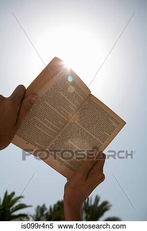 Person holding up book against the sun View Large Photo Image Stock Photography - Person holding up book against the sun. Fotosearch