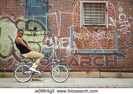 Portrait of a young woman on bicycle by wall covered in graffiti View Large Photo Image Stock Image - Portrait of a young woman on bicycle by wall covered in graffiti. Fotosearch