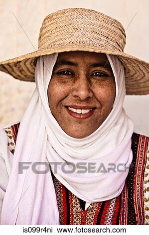 Stock Image - Portrait of a young woman wearing hat and headscarf in Djerba, Tunisia. Fotosearch