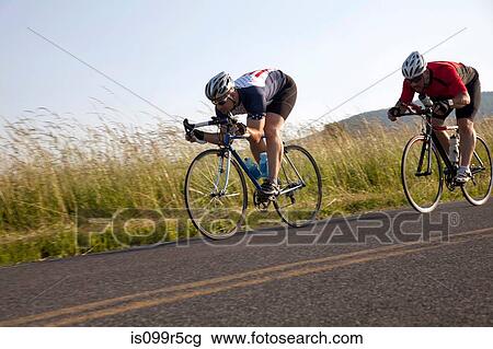 Two cyclists or road, racing downhill View Large Photo Image Stock Image - Two cyclists or road, racing downhill. Fotosearch