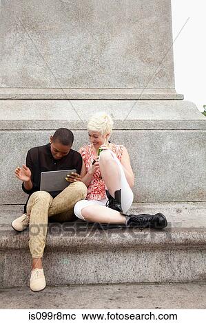 Two young women sitting on steps with digital tablet View Large Photo Image Stock Image - Two young women sitting on steps with digital tablet. Fotosearch