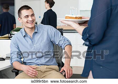 Picture - Woman bringing male colleague birthday cake in office. Fotosearch