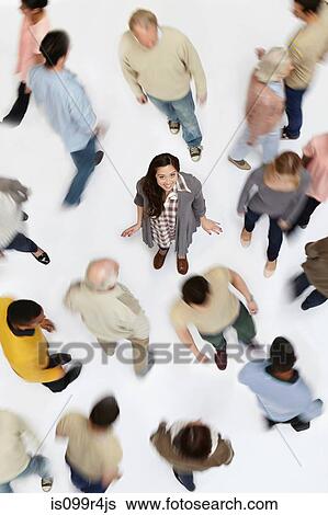 Stock Photograph - Woman standing in crowd of people, high angle view. Fotosearch