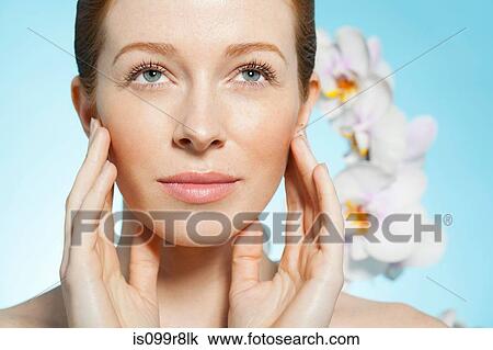 Woman touching face, orchids in background View Large Photo Image Stock Image - Woman touching face, orchids in background. Fotosearch