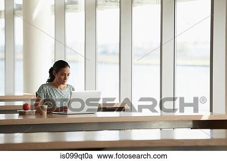 Woman using laptop with packed lunch on desk View Large Photo Image Stock Image - Woman using laptop with packed lunch on desk. Fotosearch