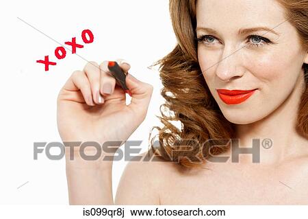 Stock Image - Woman writing kisses and hugs on glass with red lipstick. Fotosearch