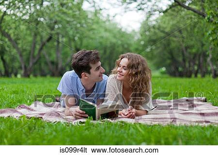 Stock Photograph - Young couple lying on blanket in park. Fotosearch