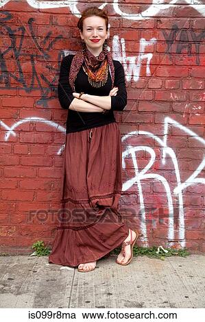 Stock Image - Young woman against wall of graffiti. Fotosearch