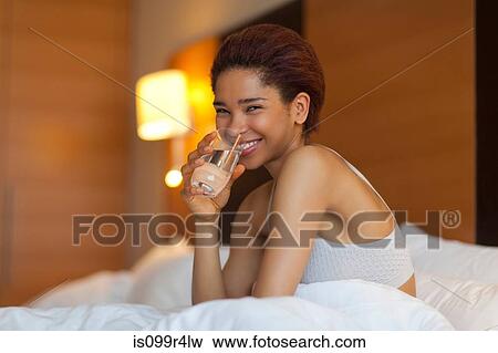 Stock Photo - Young woman drinking a glass of water in bed. Fotosearch