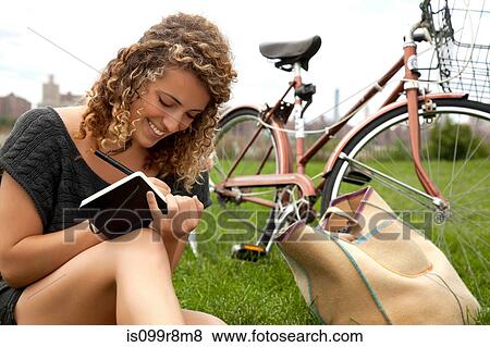Young woman in park, writing in notebook View Large Photo Image Stock Photo - Young woman in park, writing in notebook. Fotosearch