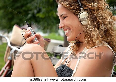 Young woman listening to music on mp3 player View Large Photo Image Picture - Young woman listening to music on mp3 player. Fotosearch