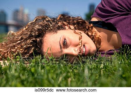 Stock Image - Young woman lying on grass. Fotosearch