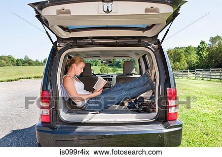 Young woman reading in back of sports utility vehicle View Large Photo Image Stock Photo - Young woman reading in back of sports utility vehicle. Fotosearch