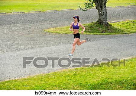 Picture - Young woman running in park. Fotosearch