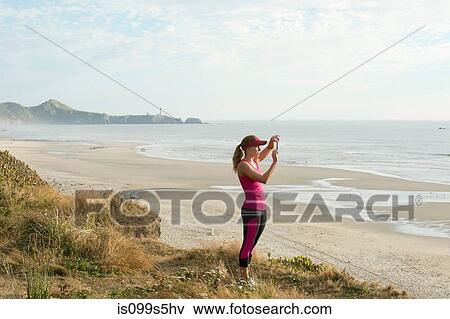Active young woman taking photograph at the beach View Large Photo Image Stock Photo - Active young woman taking photograph at the beach. Fotosearch