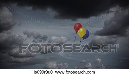 Stock Image - Balloons floating through dark sky. Fotosearch