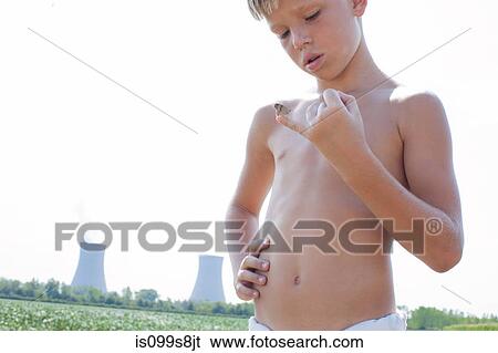 Boy holding butterfly on little finger with nuclear power station in background View Large Photo Image Stock Photograph - Boy holding butterfly on little finger with nuclear power station in background. Fotosearch