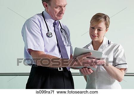 Doctor and nurse discussing medical records on digital tablet View Large Photo Image Stock Image - Doctor and nurse discussing medical records on digital tablet. Fotosearch