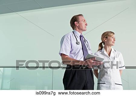 Doctor holding digital tablet with nurse View Large Photo Image Stock Image - Doctor holding digital tablet with nurse. Fotosearch