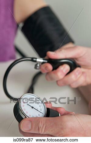 Stock Photo - Doctor using blood pressure gauge on patient during medical examination. Fotosearch