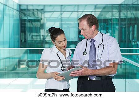 Stock Image - Doctors discussing medical records on digital tablet. Fotosearch
