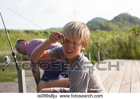 Stock Photograph - Father and son fishing, boy holding worm. Fotosearch