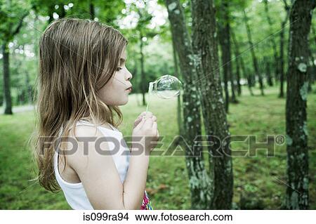 Girl blowing bubbles in forest View Large Photo Image Picture - Girl blowing bubbles in forest. Fotosearch