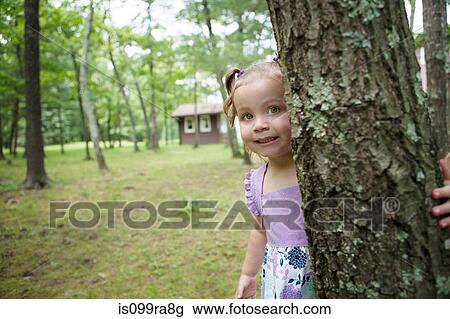 Stock Image - Girl hiding behind tree. Fotosearch