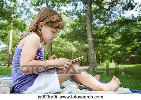 Girl sitting on picnic blanket with digital tablet View Large Photo Image Stock Image - Girl sitting on picnic blanket with digital tablet. Fotosearch