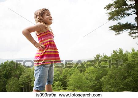 Stock Image - Girl with hands on hips near forest. Fotosearch