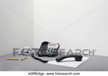 Picture - Landline office phone off the hook with pencil and paper. Fotosearch