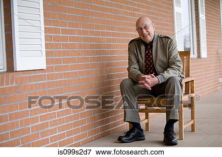 Stock Photo - Man sitting on chair, portrait. Fotosearch
