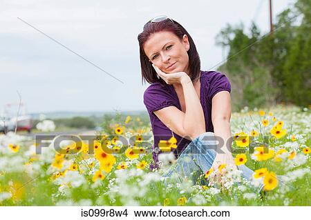Mid adult woman sitting in a field of flowers View Large Photo Image Picture - Mid adult woman sitting in a field of flowers. Fotosearch