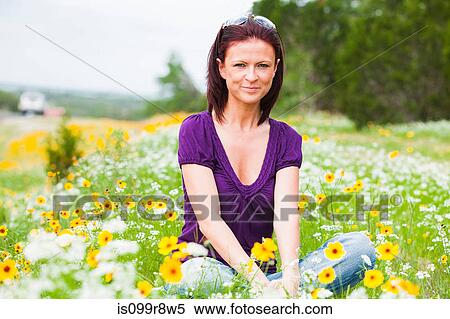 Mid adult woman sitting in a field of flowers View Large Photo Image Stock Photography - Mid adult woman sitting in a field of flowers. Fotosearch