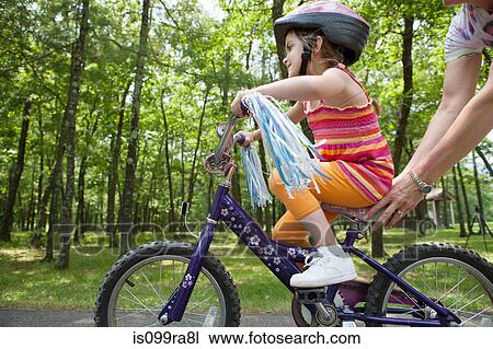 Mother helping daughter to ride bicycle View Large Photo Image Stock Image - Mother helping daughter to ride bicycle. Fotosearch