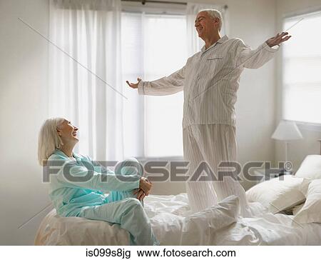 Stock Image - Senior couple fooling around on bed. Fotosearch