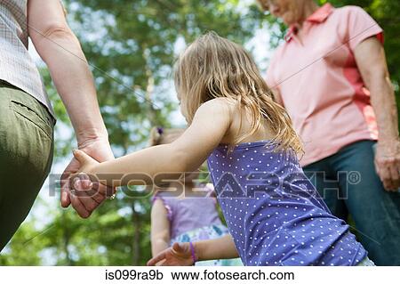 Stock Image - Three genration family holding hands, candid. Fotosearch
