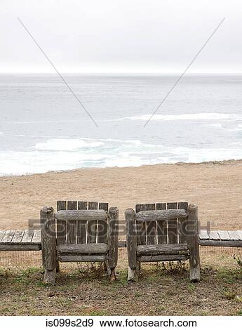 Stock Photo - Two empty wooden chairs on beach. Fotosearch