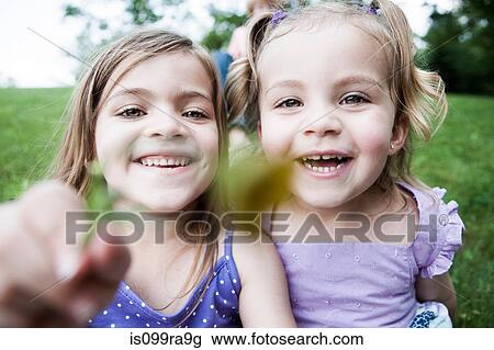 Two girls holding flower to camera, close up View Large Photo Image Stock Image - Two girls holding flower to camera, close up. Fotosearch