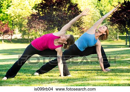 Two women practising yoga together in a park View Large Photo Image Picture - Two women practising yoga together in a park. Fotosearch