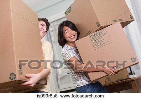 Stock Photo - Two young women moving boxes. Fotosearch